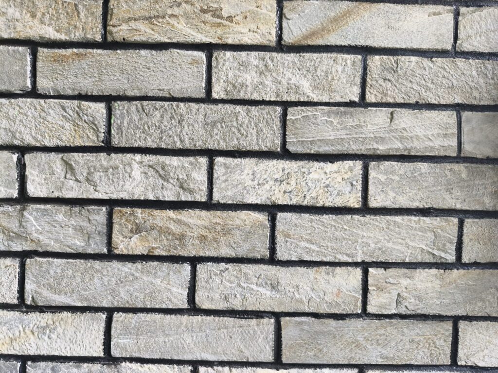 Close view of a wall of pale rough-faced stone bricks with dark mortar joints