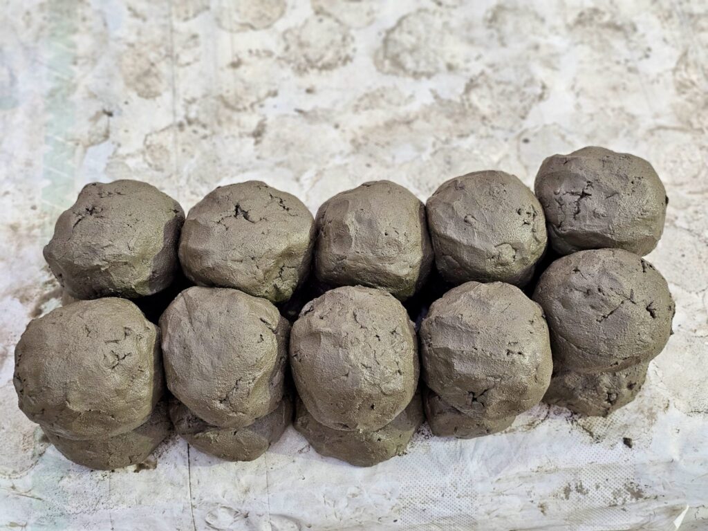 Ten balls of grey clay stacked in two rows on a pale surface