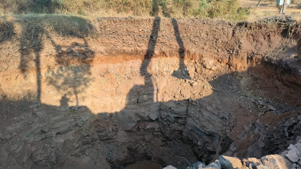 Orange and brown layers of soil and rock exposed in the wall of a deep excavation